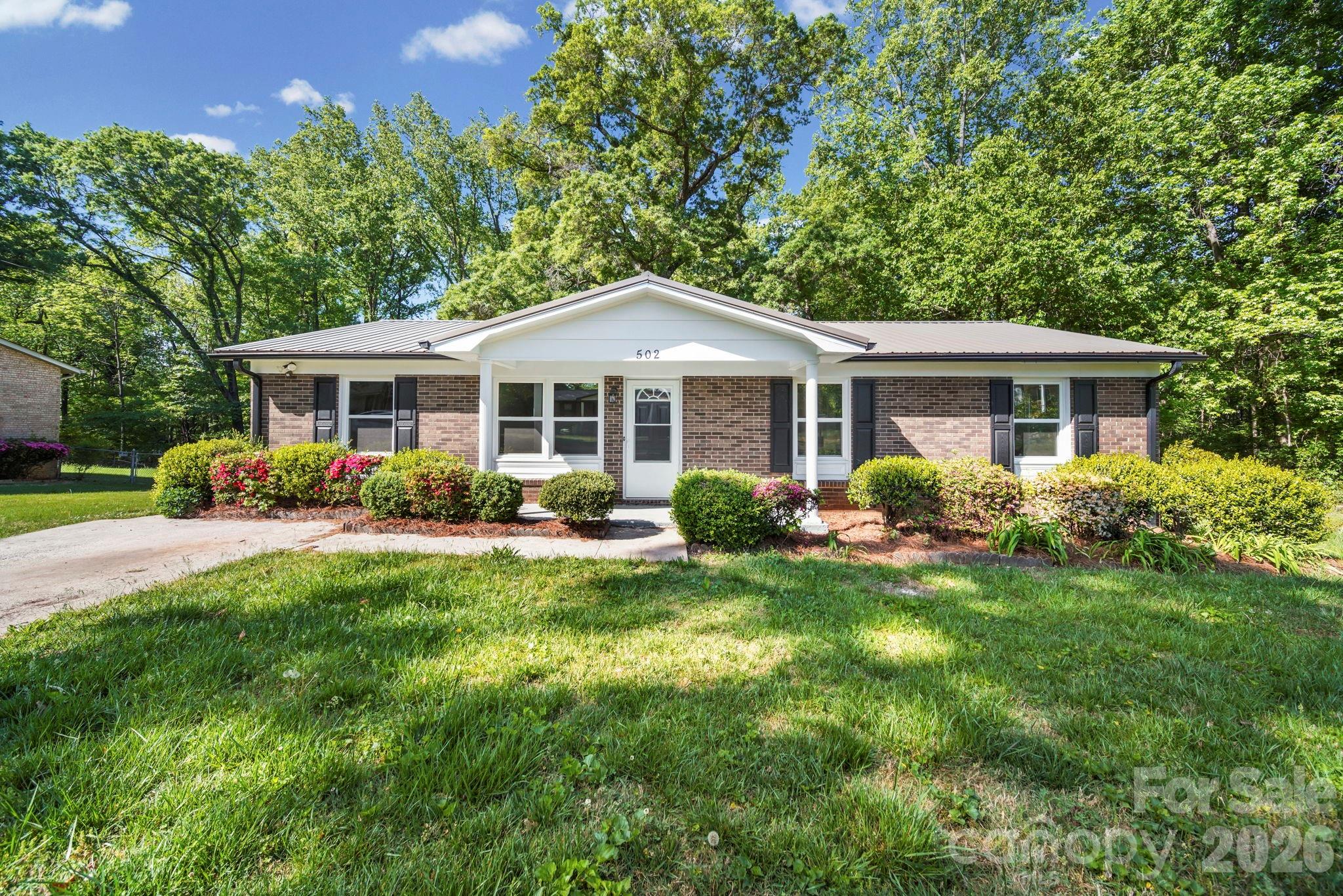 a front view of a house with a yard and trees