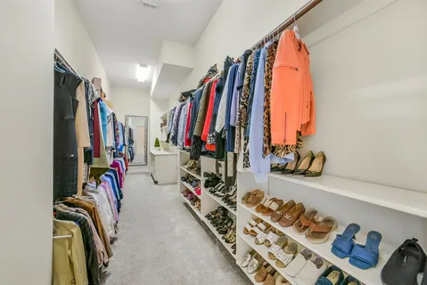 a view of walk in closet with clothes and shoes