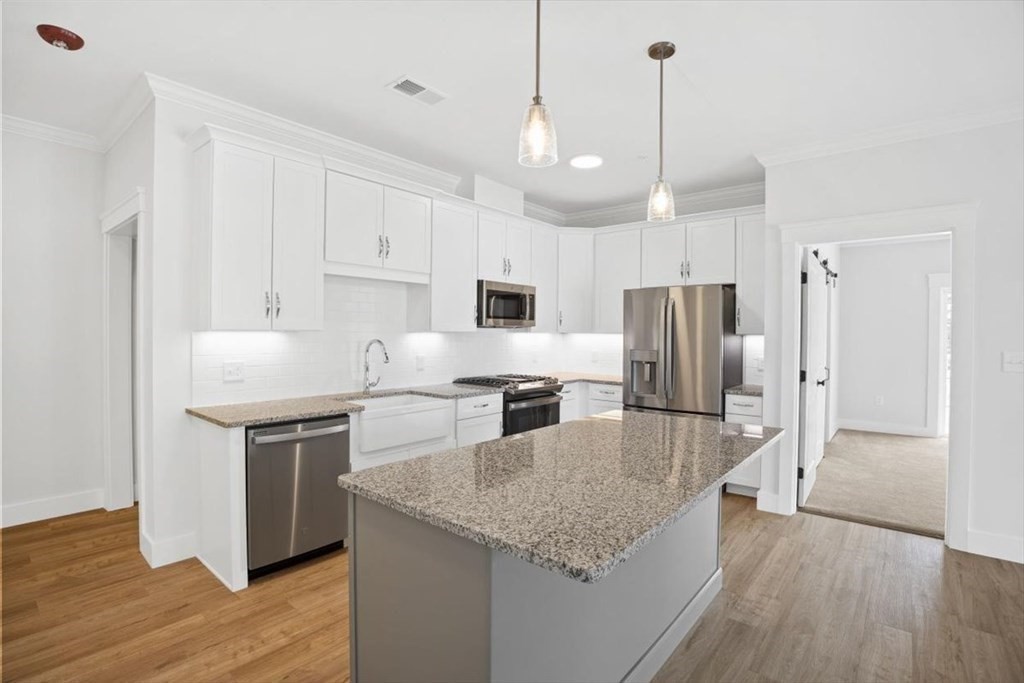 a kitchen with kitchen island a counter space a sink appliances and cabinets