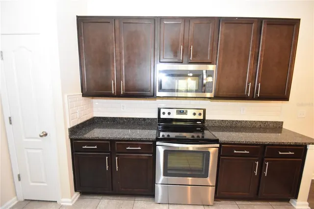 a kitchen with granite countertop a stove and a microwave