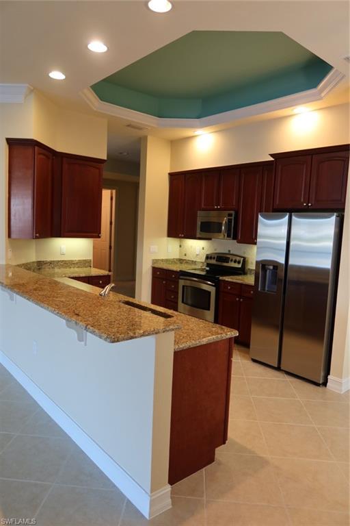 7168 Lemuria Circle, Unit 1701 Naples, FL 34109 - Photo 5 of 39 Kitchen featuring warm wood cabinetry, granite countertops, and stainless steel appliances