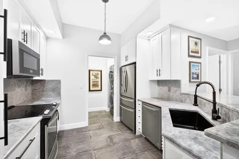 a kitchen with stainless steel appliances granite countertop a sink a stove and a refrigerator