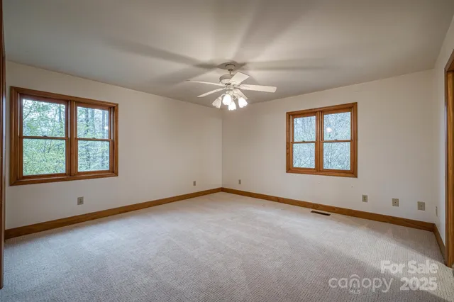an empty room with windows and ceiling fan