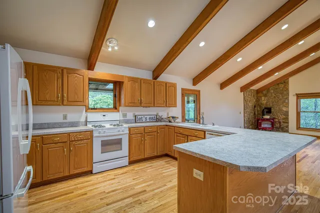 a kitchen with a stove a sink dishwasher a kitchen island with wooden cabinets and floor