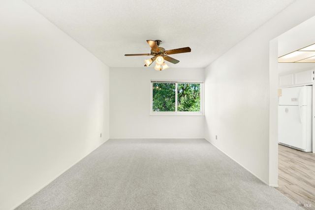 an empty room with windows and a ceiling fan