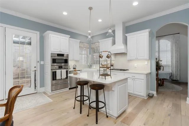 a kitchen with kitchen island a white counter top space a sink stainless steel appliances and cabinets