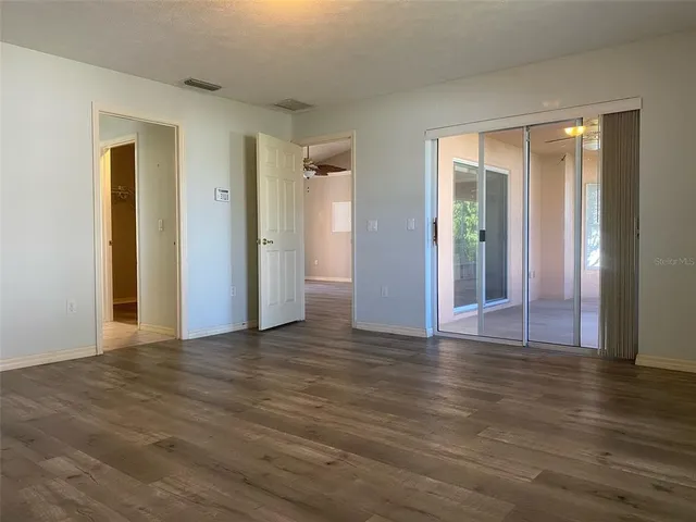 a view of an empty room with wooden floor and window