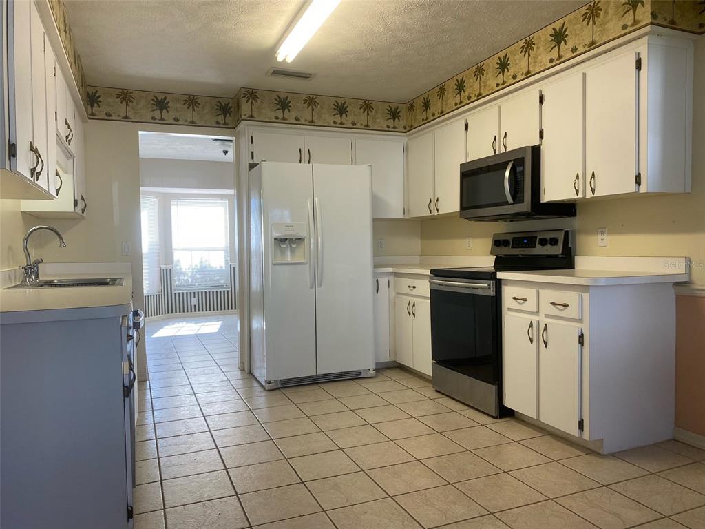 5881 Southwest 86th Place Ocala, FL 34476 - Photo 8 of 18 a kitchen with stainless steel appliances a stove refrigerator sink and cabinets