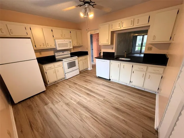 a kitchen with granite countertop white cabinets and white appliances