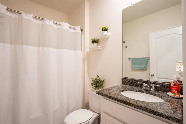 a bathroom with a granite countertop sink and a mirror with toilet