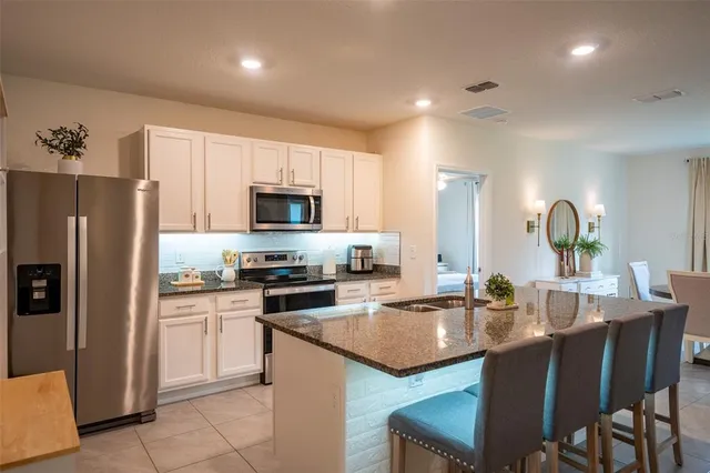 a kitchen with a sink a microwave a refrigerator and chairs