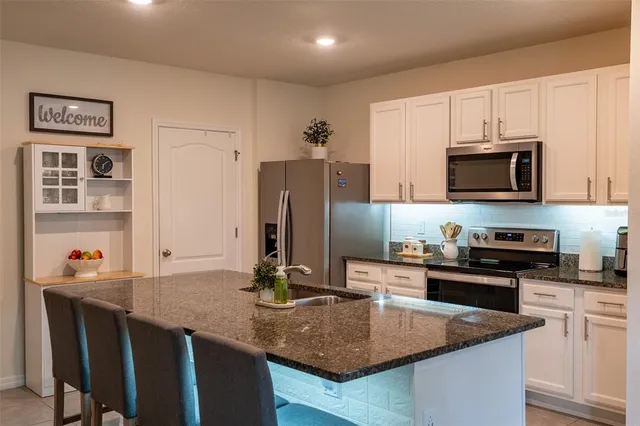 a kitchen with stainless steel appliances granite countertop a sink a stove a microwave a refrigerator and cabinets