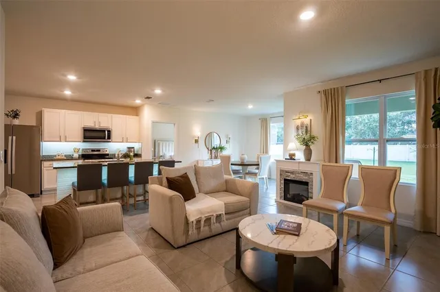a living room with furniture kitchen view and a large window