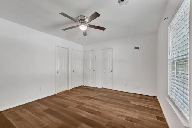 a view of empty room with wooden floor and fan