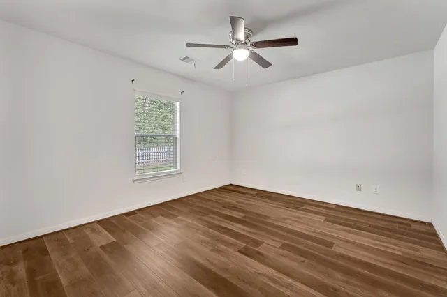 an empty room with a window and a ceiling fan