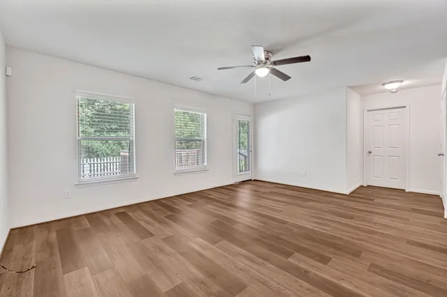 a view of an empty room with wooden floor and a window
