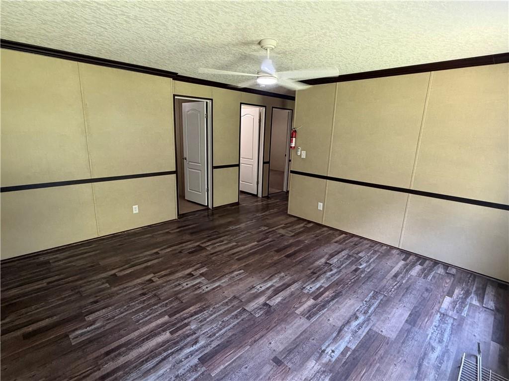 158 Kite Road Pittsview, AL 36871 - Photo 19 of 32 Spacious room featuring wood-finish flooring, a ceiling fan with integrated lighting, and light-toned wall panels with dark trim