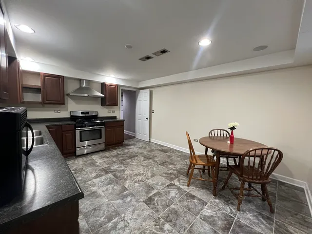 a kitchen with stainless steel appliances granite countertop a sink dishwasher a stove a refrigerator with a dining table and chairs