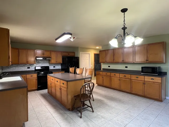 a kitchen with stainless steel appliances granite countertop a sink a stove and a wooden cabinets