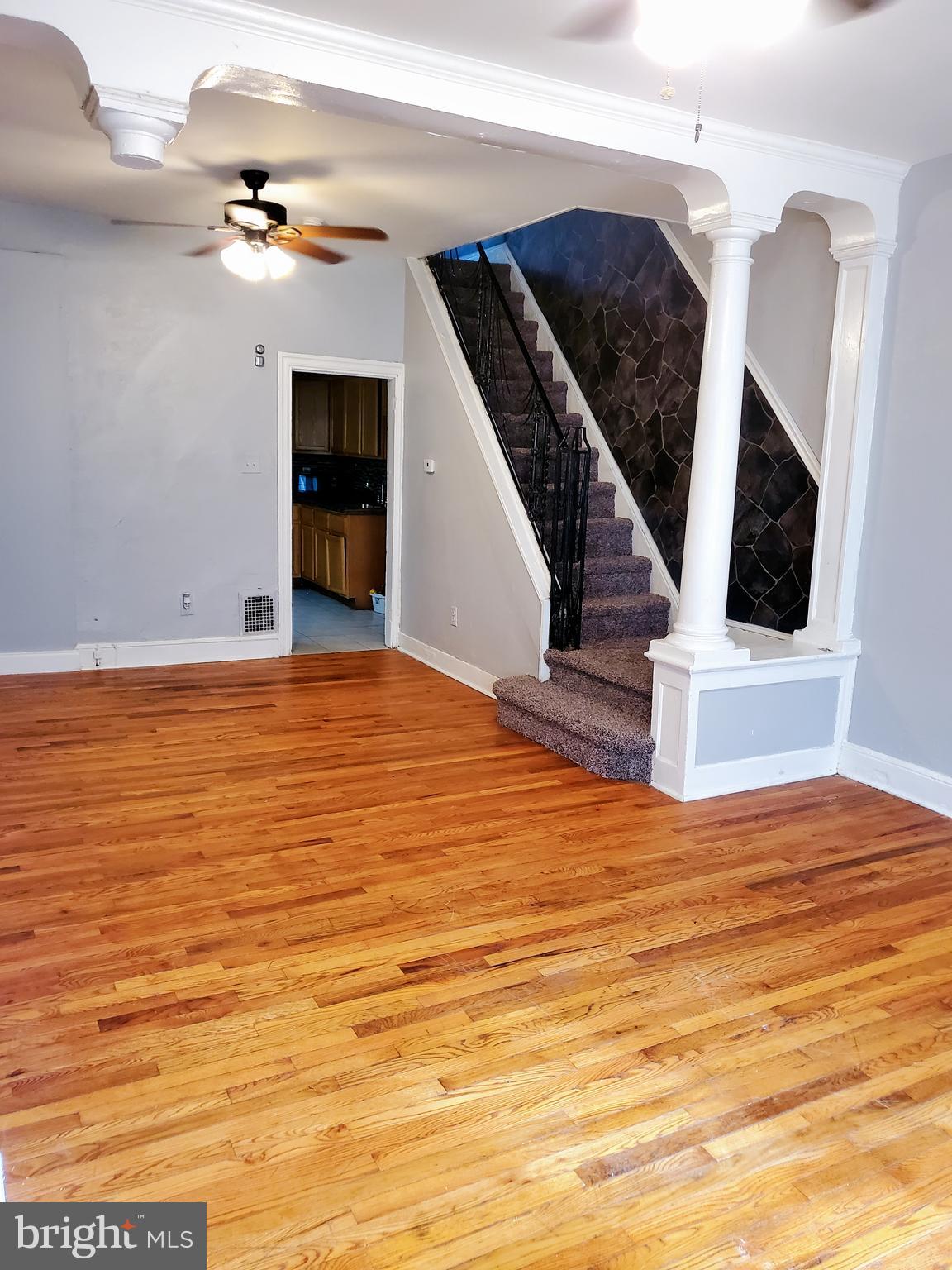 a view of an empty room with wooden floor and fireplace