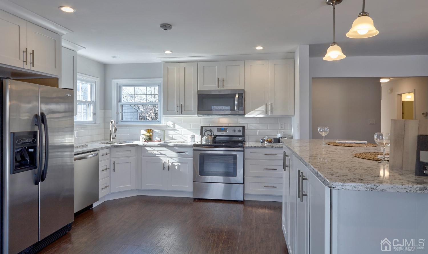a kitchen with granite countertop a refrigerator stove top oven and sink