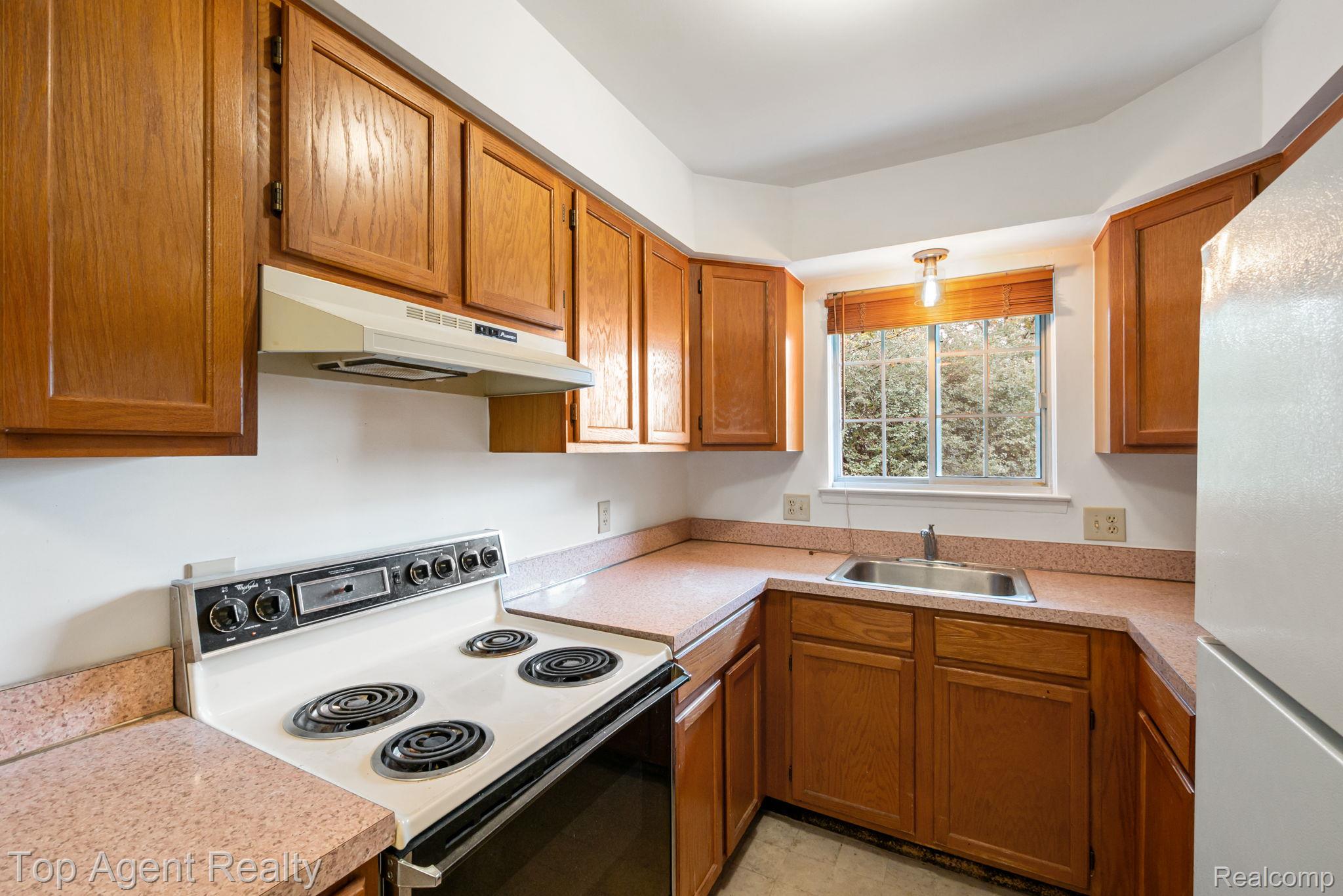 23420 Middlebelt Road Farmington, MI 48336 - Photo 13 of 32 Kitchen featuring wood-finish cabinetry, solid surface countertops, and a stainless steel sink