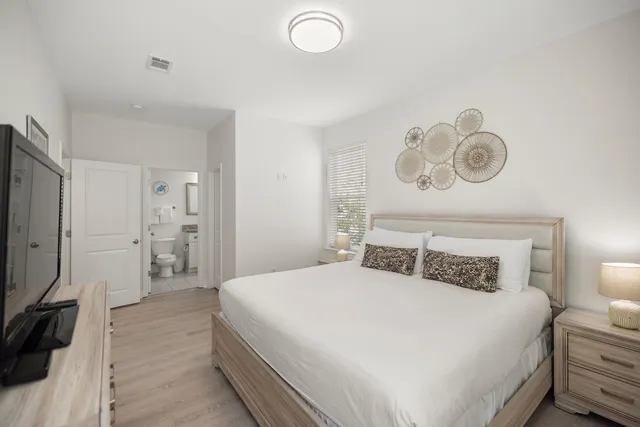 a spacious bedroom with a bed and a flat screen tv