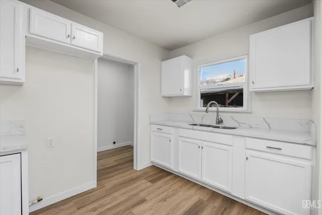 a kitchen with white cabinets and sink