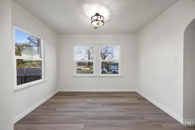 a view of an empty room with wooden floor and window