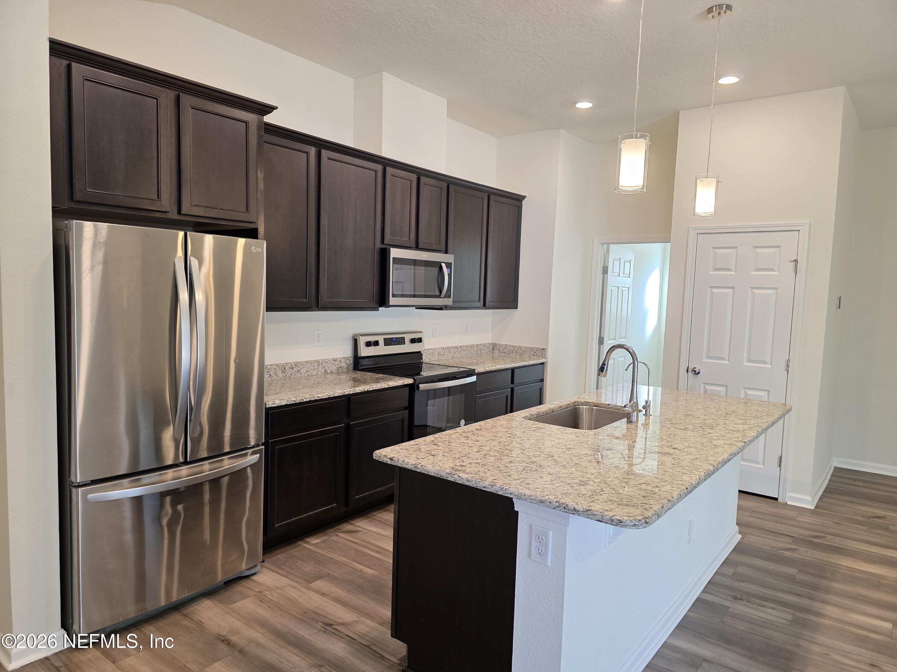 3035 Lucille Lane Middleburg, FL 32068 - Photo 8 of 39 a kitchen with kitchen island granite countertop wooden cabinets a refrigerator and a stove top oven