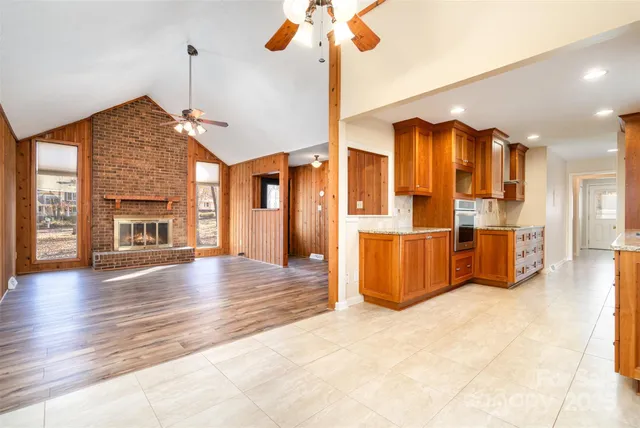 an empty room with wooden floor fireplace and windows