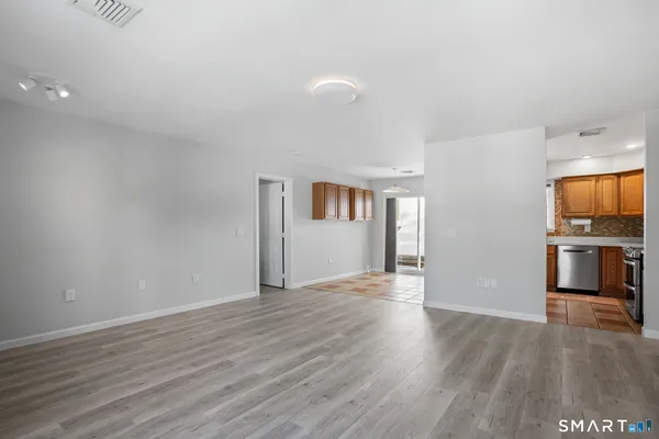 a view of a kitchen with an empty room and wooden floor