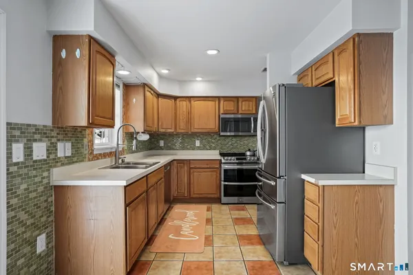 a kitchen with stainless steel appliances granite countertop a sink stove refrigerator and cabinets