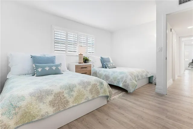 a bedroom with two beds and wooden floor