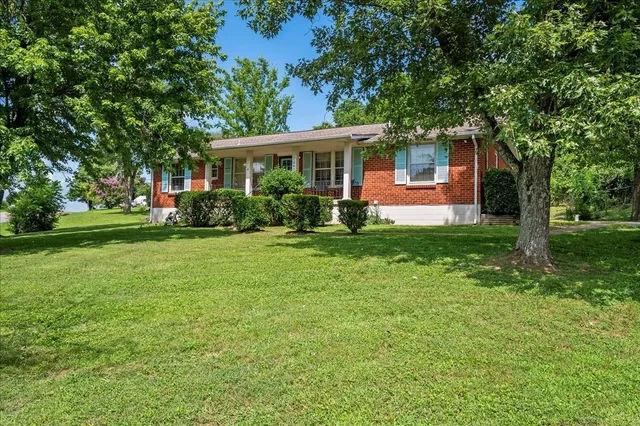 a front view of a house with a yard and tree