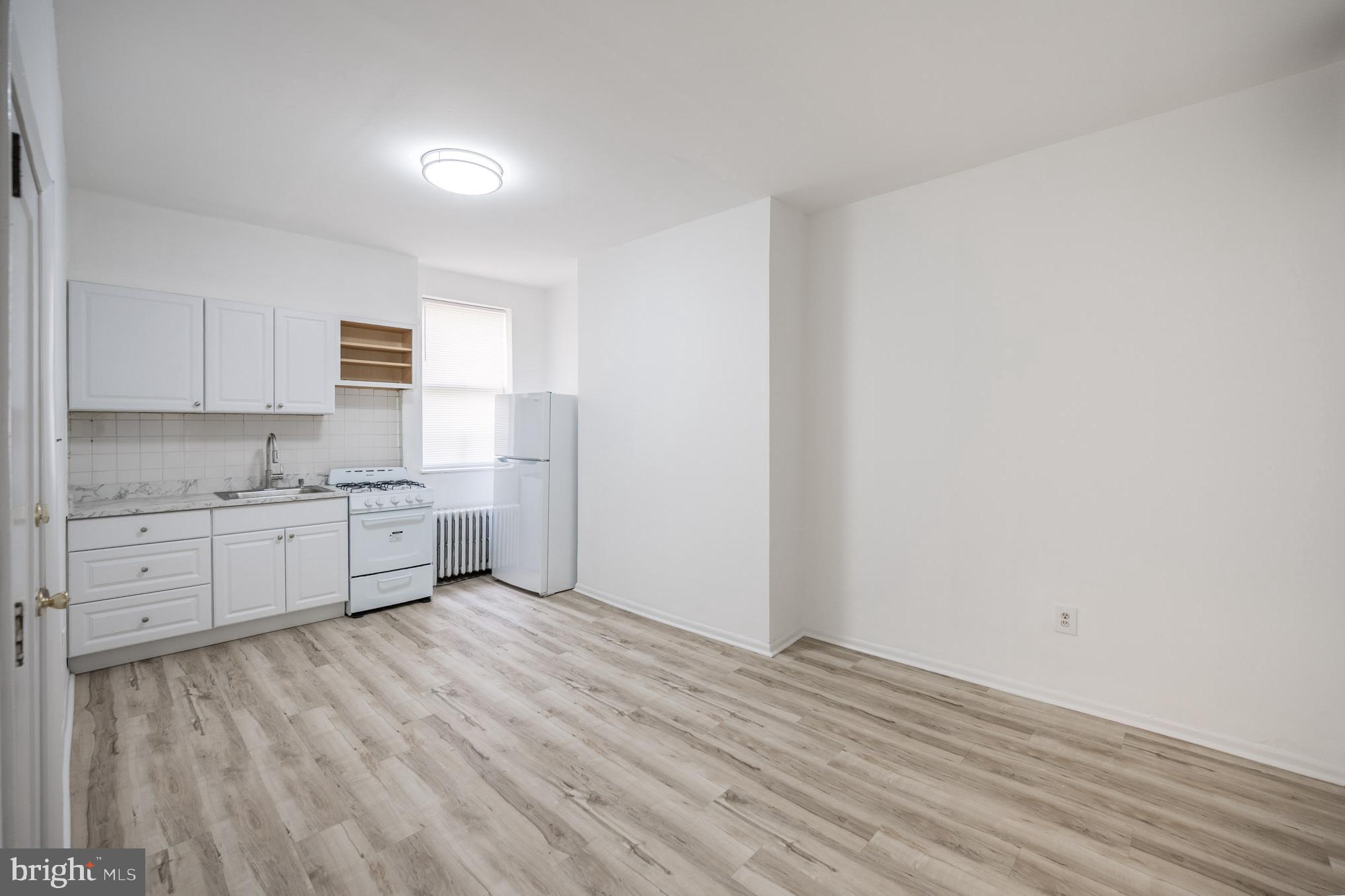 625 South 10th Street, Unit 2F Philadelphia, PA 19147 - Photo 1 of 13 a view of a kitchen with white cabinets and wooden floor