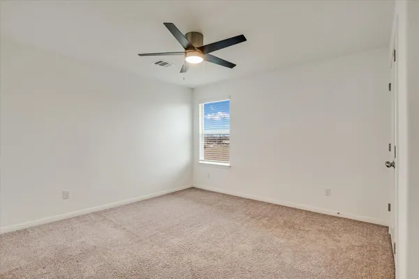 an empty room with ceiling fan and window