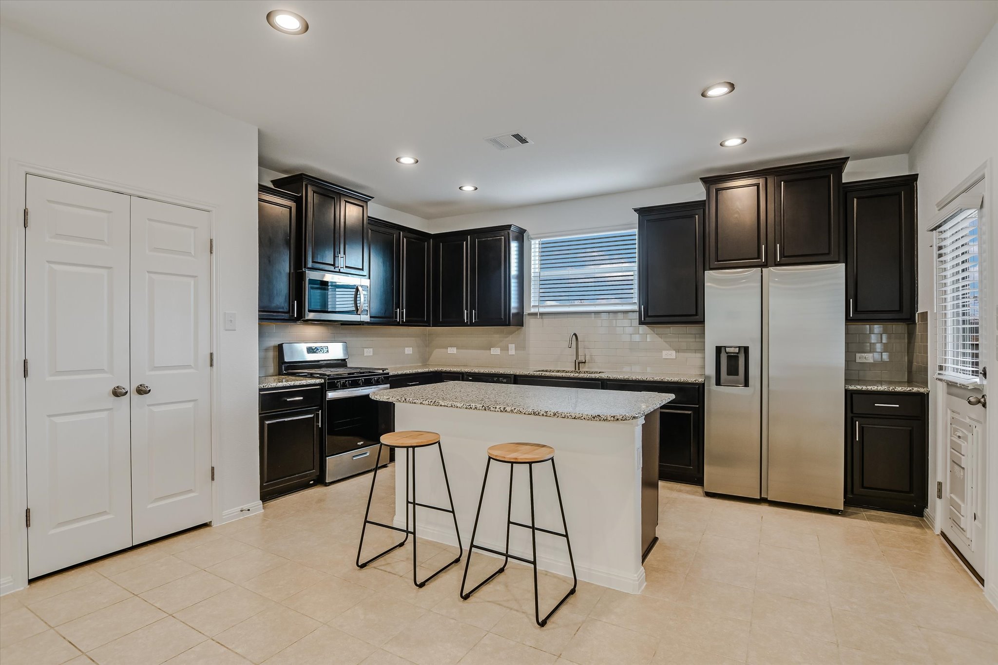12814 Meachum Lane Manor, TX 78653 - Photo 6 of 20 a kitchen with stainless steel appliances granite countertop a refrigerator a stove a sink and a microwave