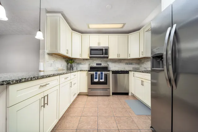 a kitchen with stainless steel appliances granite countertop a refrigerator and a stove