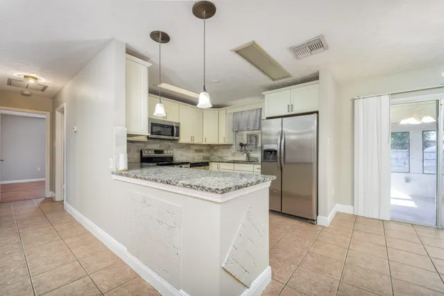 a kitchen with stainless steel appliances granite countertop a refrigerator a stove and a sink