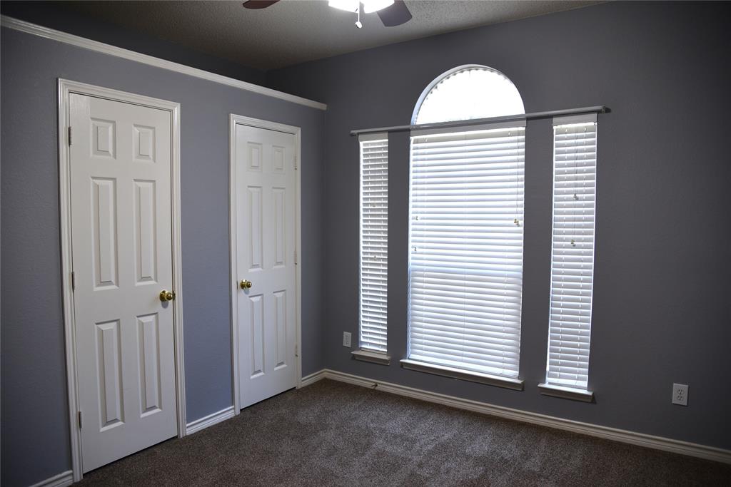 1526 Pebblestone Court Allen, TX 75002 - Photo 18 of 28 Room featuring a large arched window with horizontal blinds, two paneled doors with brass hardware, and crown molding