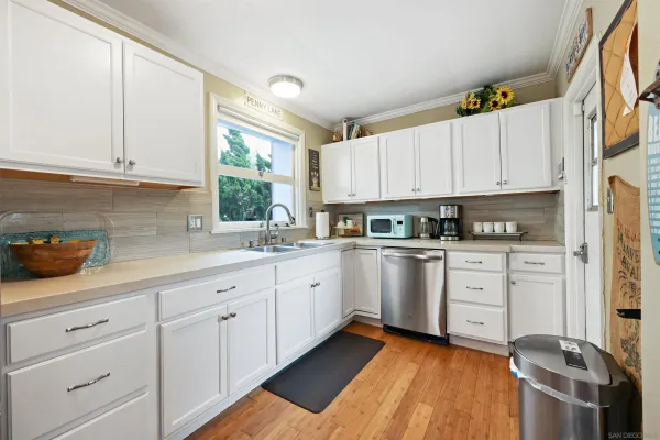 a kitchen with granite countertop white cabinets stainless steel appliances a sink and a window