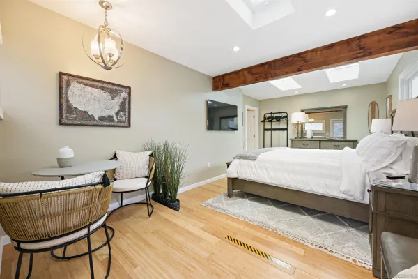 a spacious bedroom with a bed a chandelier and mirror