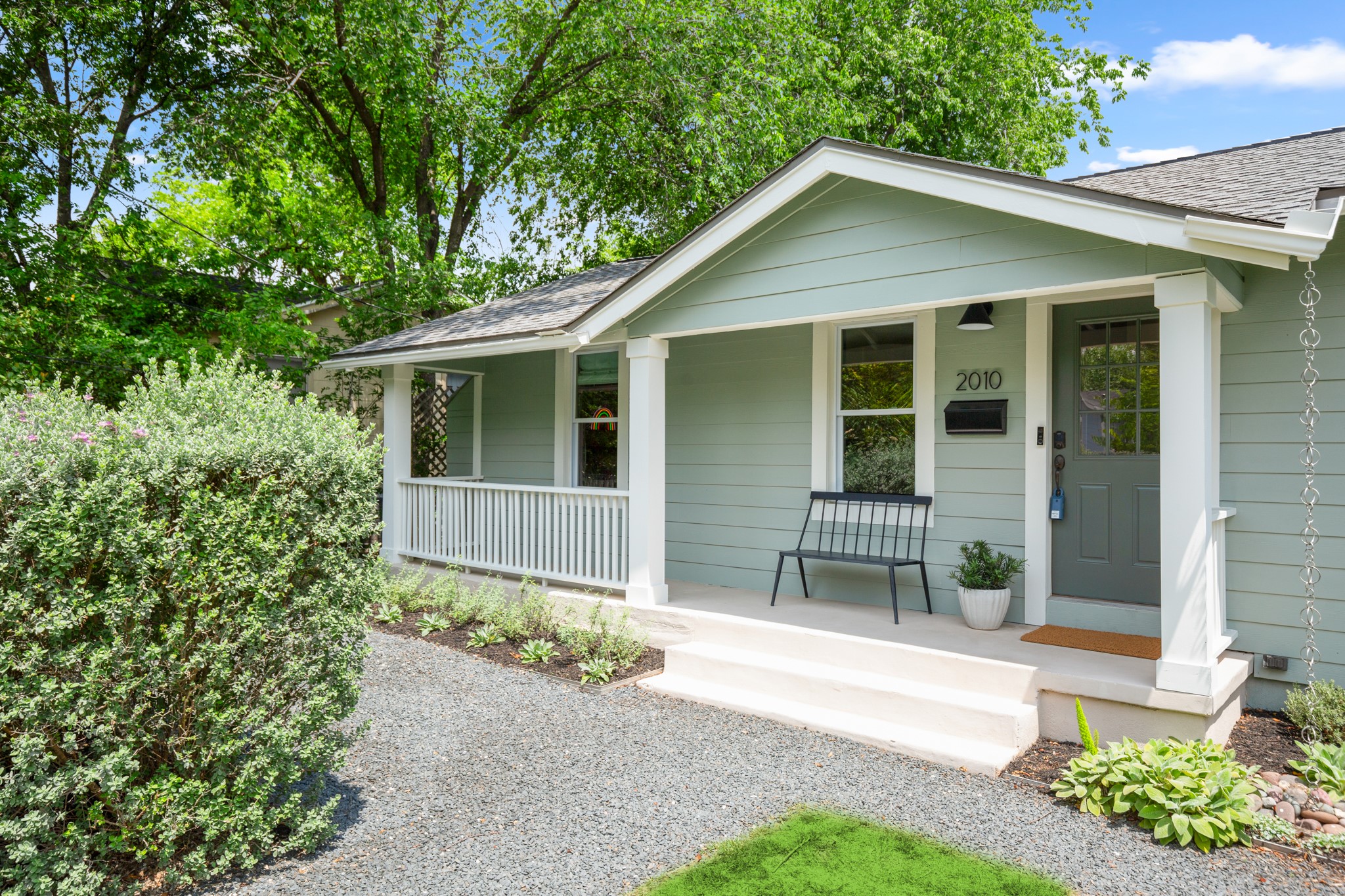 2010 Alegria Road Austin, TX 78757 - Photo 2 of 35 Light green siding exterior with a covered porch featuring white columns and railing