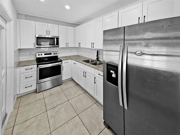 a kitchen with stainless steel appliances granite countertop a refrigerator a stove and a sink