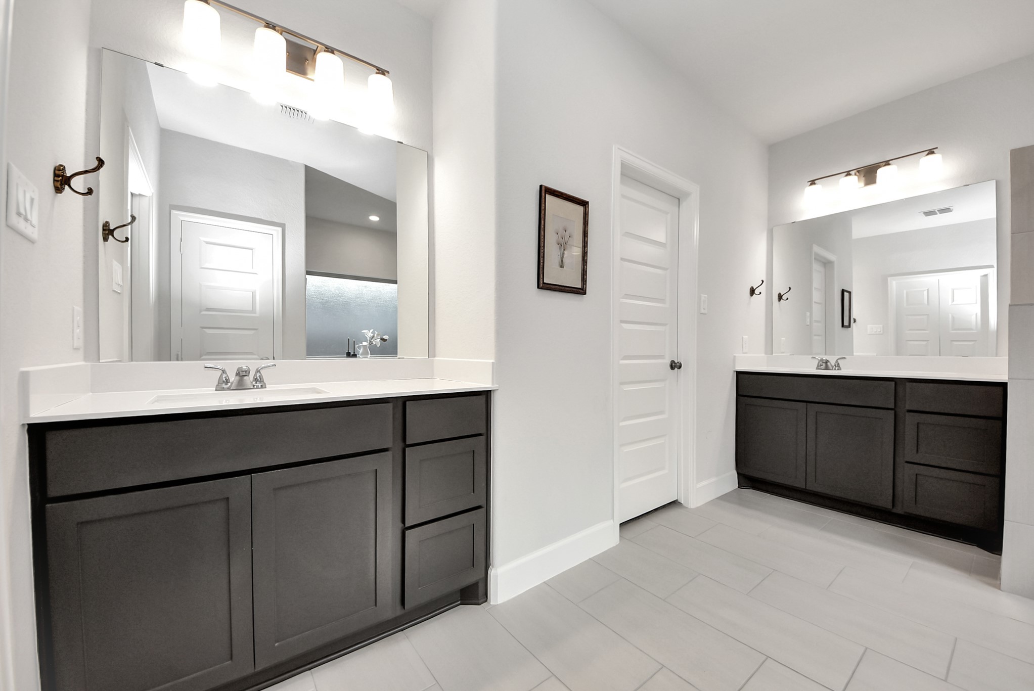 42546 Summer Crst Road Magnolia, TX 77354 - Photo 16 of 27 This modern owners bathroom features dual vanities with dark cabinetry, large mirrors, and bright overhead lighting.