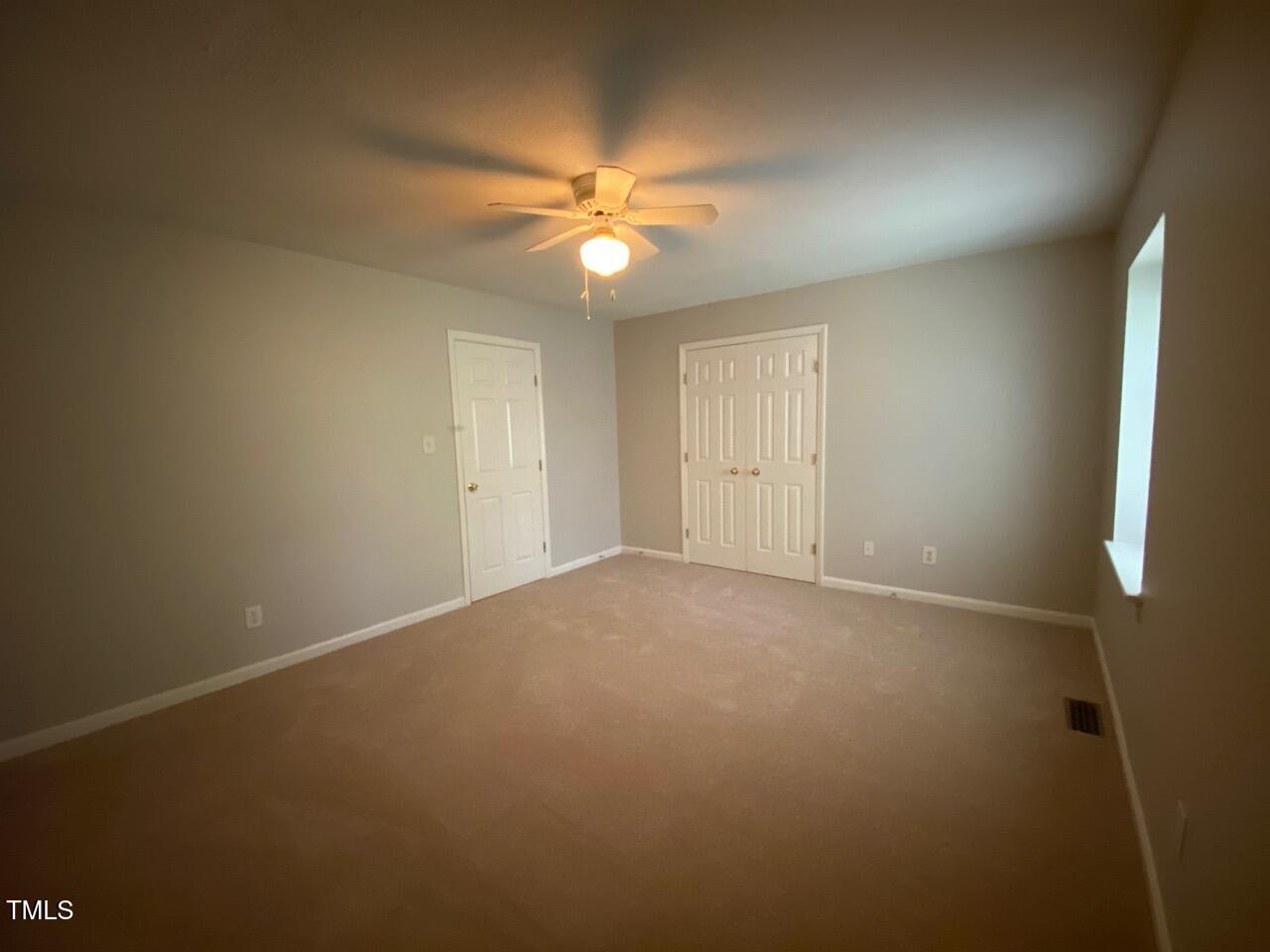 4706 Blue Bird Court, Unit I Raleigh, NC 27606 - Photo 12 of 16 an empty room with a fan and a fan