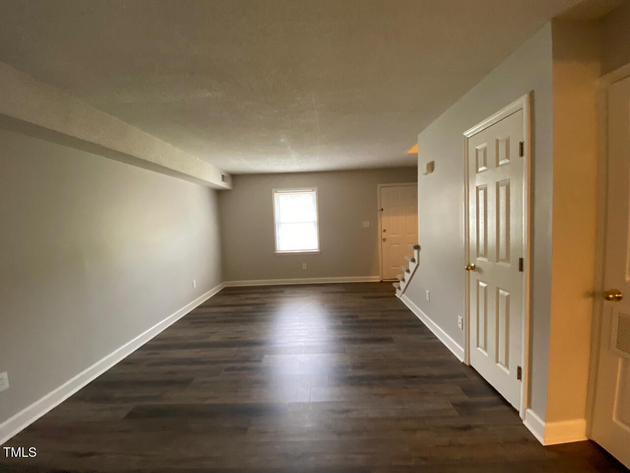 4706 Blue Bird Court, Unit I Raleigh, NC 27606 - Photo 5 of 16 a view of an empty room with wooden floor and a window
