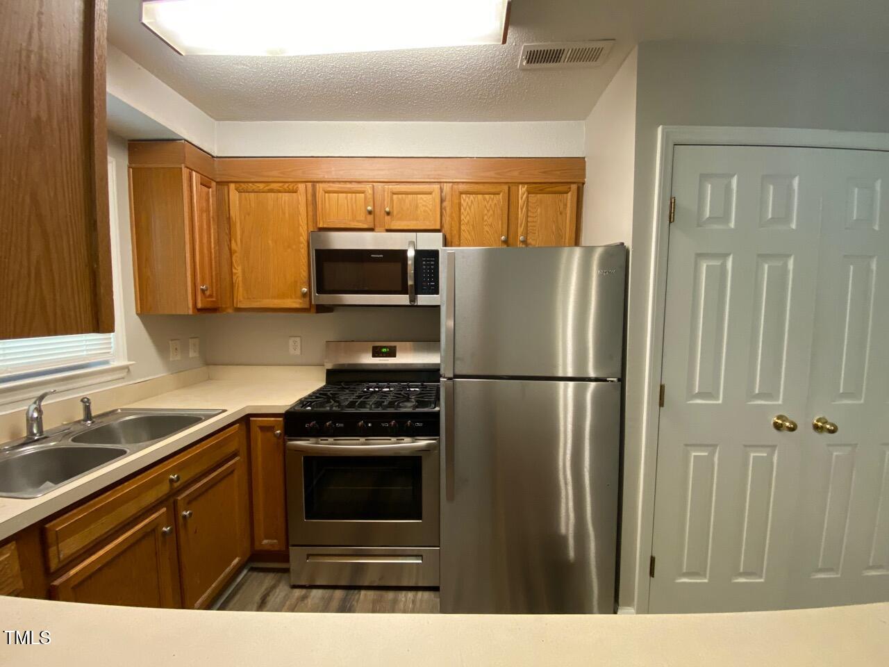 4706 Blue Bird Court, Unit I Raleigh, NC 27606 - Photo 8 of 16 a kitchen with a refrigerator stove and sink