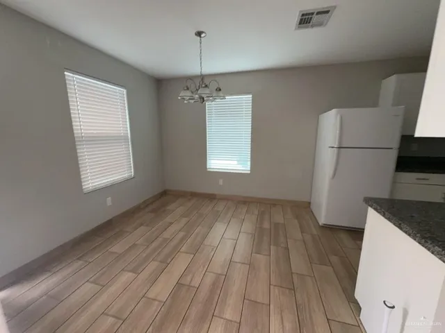 an empty room with a chandelier fan and windows